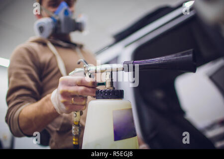 Nettoyage voiture employé salon avec de la vapeur chaude. Notion d'équipement propre et sec hors focus Banque D'Images