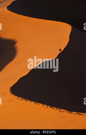 Man climbing sand dunes, Parc National Namib Naukluft, Namibie Banque D'Images