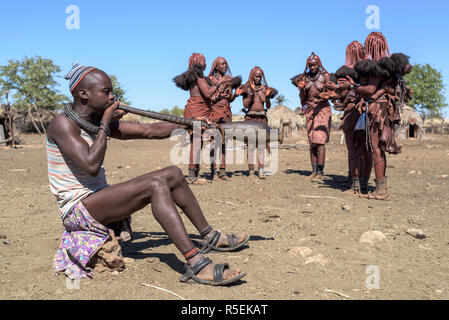 Groupe des femmes Himba avec costumes traditionnels de danser dans un cercle alors qu'un homme joue un violon fabriqué à partir d'une corne orix. Banque D'Images