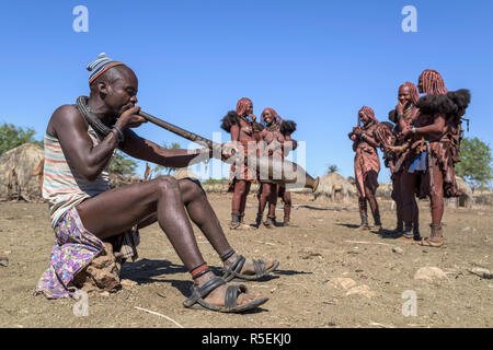 Groupe des femmes Himba avec costumes traditionnels de danser dans un cercle alors qu'un homme joue un violon fabriqué à partir d'une corne orix. Banque D'Images