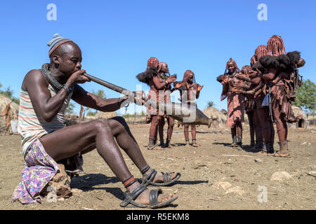 Groupe des femmes Himba avec costumes traditionnels de danser dans un cercle alors qu'un homme joue un violon fabriqué à partir d'une corne orix. Banque D'Images