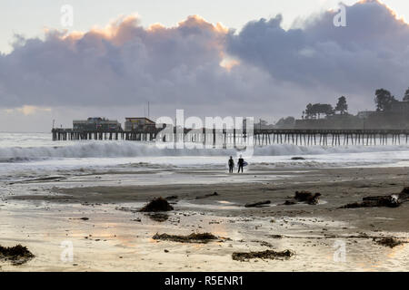 Capitola Beach et quai dans les nuages orageux coucher du soleil et des surfeurs d'ossature. Banque D'Images