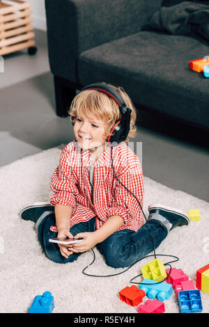 High angle view of smiling child listening music dans les écouteurs à la maison Banque D'Images