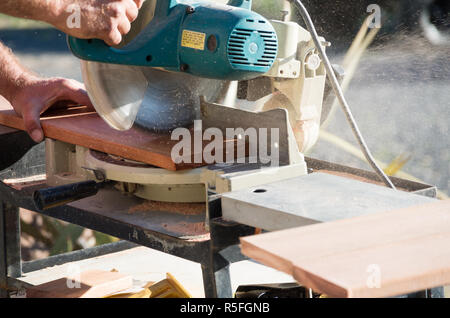 Homme couper du bois avec une scie à l'extérieur au soleil pendant les rénovations dans l'après-midi Banque D'Images