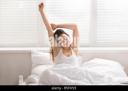 Happy Woman Stretching On Bed Banque D'Images