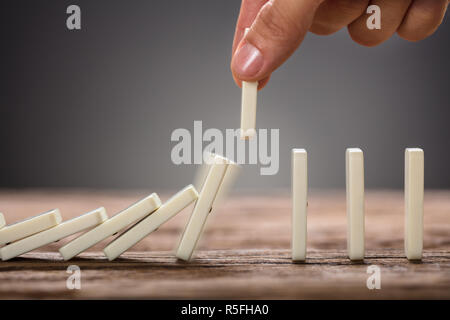 Businessman Picking Pièce Domino sur table en bois Banque D'Images