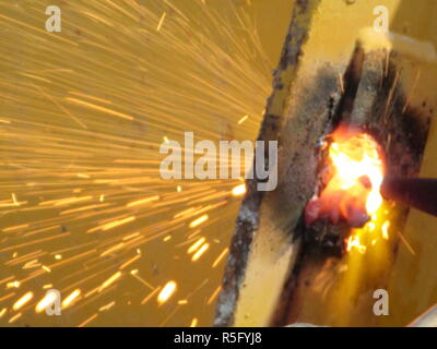 Petites étincelles de feu à partir de machines de découpe de l'acier lorsque les hommes sont à l'aide de la meuleuse disque pour couper l'acier ou la soudure de l'oxygène pour souder des pièces en acier ensemble Banque D'Images