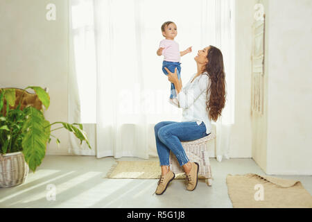 Mère brunette joue avec l'enfant à la maison. Banque D'Images