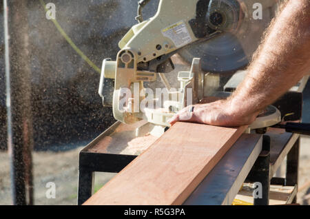 Homme couper du bois avec une scie à l'extérieur au soleil pendant les rénovations dans l'après-midi Banque D'Images