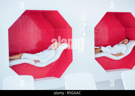 Couple allongé sur des transats en mosaïque octogones à spa Banque D'Images