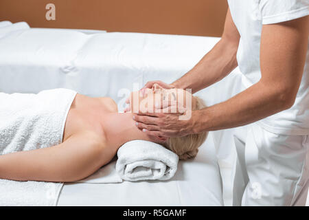 Masseur masculin faisant face massage pour femme en salle de spa Banque D'Images