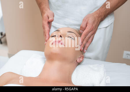 Masseur masculin faire massage visage de femme dans spa salon Banque D'Images