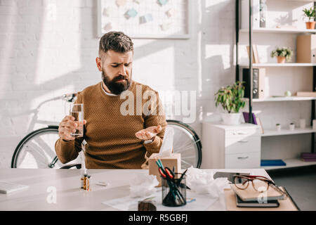 Sick businessman sitting at Office 24, holding glass of water, et de médecine de travail Banque D'Images