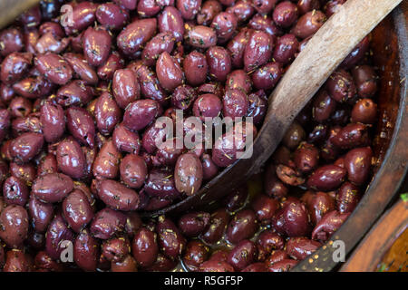 Olives en bols en bois avec une cuillère de service. Banque D'Images