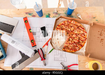 Vue de dessus de la boîte avec la pizza, outils et plan de construction sur smartphone Banque D'Images