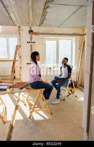 Happy young couple eating pizza tout en effectuant la rénovation d'accueil Banque D'Images