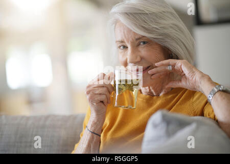 Belle femme senior à la maison avec une tasse de thé en feuilles Banque D'Images