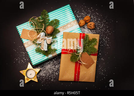 Décorées de couleurs et des cadeaux de Noël sur fond noir avec de la neige, des noix et une bougie Banque D'Images