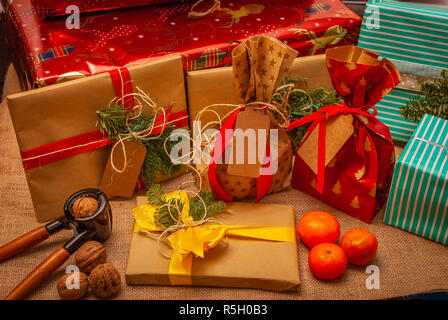 Cadeaux de Noël coloré décoré avec des noix, noisette, fruits et branches vertes Banque D'Images