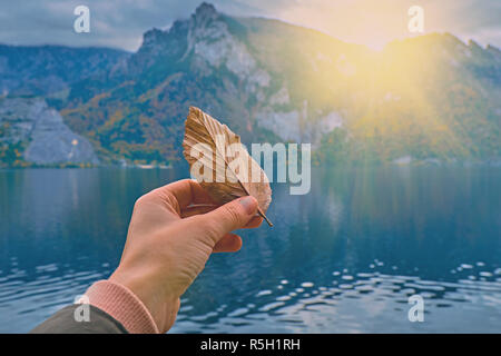 Jeune fille s'hollding vert pâle dans sa main dans la lumière vive du soleil lever du soleil panoramique magnifique sur le lac Alpes autrichiennes. Je voyage vacances Hipster Banque D'Images