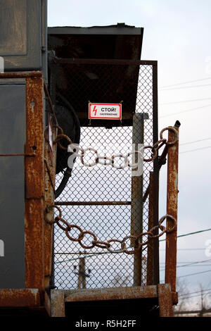 Boîte de transformateur à une hauteur, entourée d'une chaîne et une inscription en russe : Tension d'arrêt Banque D'Images