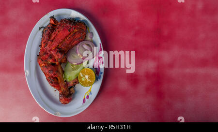 Les aliments indiens authentiques de Malaisie - restaurant de la rue de la famille. Plaque de poulet Tandoori épicés isolé sur fond rouge. Delicious Banque D'Images