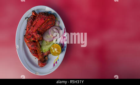 Les aliments indiens authentiques de Malaisie - restaurant de la rue de la famille. Plaque de poulet Tandoori épicés isolé sur fond rouge avec l'article pour le texte. Delici Banque D'Images