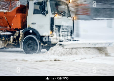 Camion chasse-neige supprime la neige de la route de la ville. Tempête dans la ville - l'arrière-plan flou abstrait de saison Banque D'Images