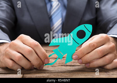 Businessman Holding Livre Vert Rocket At Table Banque D'Images