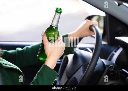 Close-up of a female Hand Holding Alcoholic Bouteille Driving Car Banque D'Images