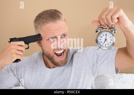 Angry Man Holding Gun et Réveil Banque D'Images