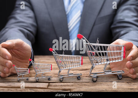 Businessman couvrant divers Shopping Carts sur table Banque D'Images