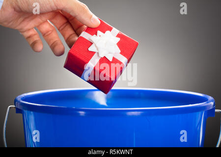 Businessman's Hand Throwing boîte-cadeau en seau bleu Banque D'Images