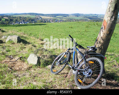 Vue sur Schlettau dans les montagnes de l'Ore avec vélo tout-terrain appuyé contre un oiseau Banque D'Images