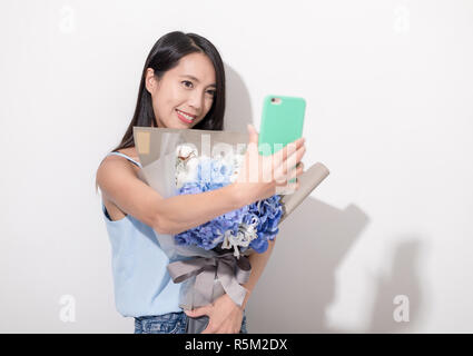 Woman holding bouquet de fleurs et la prise de téléphone mobile avec des selfies Banque D'Images