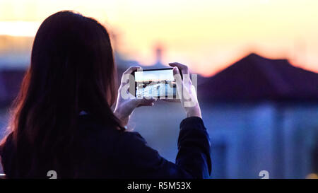 Vue arrière d'une femme à prendre des photos avec son mobile sur le Grand Canal à Venise, Italie. Banque D'Images