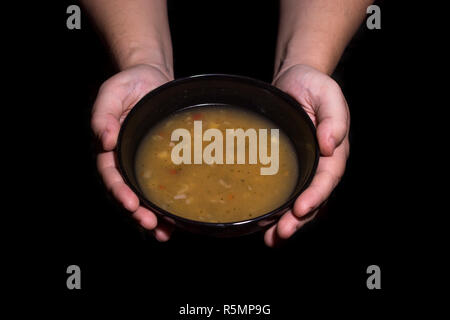 Concept de la pauvreté. Homme tenant un bol de soupe isolé sur fond noir. Banque D'Images