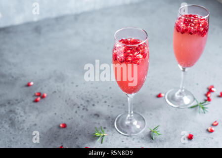 Champagne Cocktail Grenade Mimosa (cocktails sans alcool) au romarin sur fond de béton, de copier l'espace. Mimosa boisson pour la Saint-Valentin ou autres jours fériés. Banque D'Images