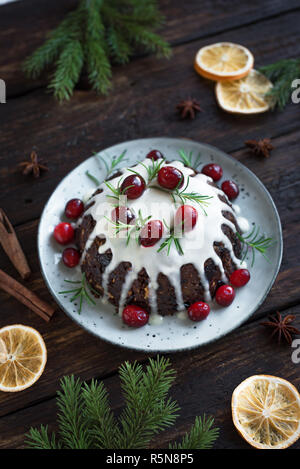 Le pudding de Noël, fruits gâteau décoré avec du glaçage et des canneberges sur table en bois rustique, vue du dessus. Le dessert traditionnel de Noël fait maison - Christma Banque D'Images