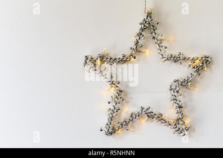 L'étoile de Noël avec des lumières accroché sur mur blanc Banque D'Images