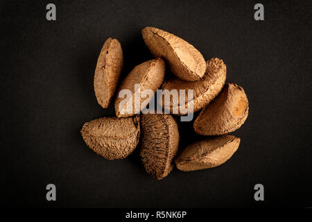 Petit tas de matières brown noix du Brésil en leurs coquillages naturels, vues de dessus, isolé sur fond noir Banque D'Images