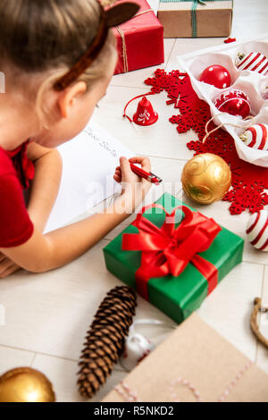 Cute girl écrit lettre au Père sur salon-de-chaussée. Jeune fille écrit sa liste de cadeaux de Noël. Banque D'Images