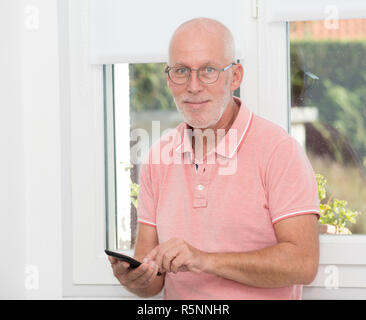 Homme mature avec des lunettes de taper un message sur smartphone Banque D'Images