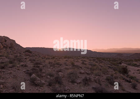 Panorama magnifique du Désert de Mojave, au coucher du soleil. Terrain rocheux où la végétation est clairsemée et la chaîne de montagnes sur l'horizon. Banque D'Images