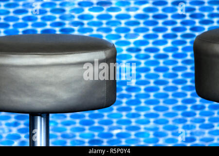 Tabouret de bar en cuir noir moderne devant un fond bleu vif, tuile au détail Banque D'Images