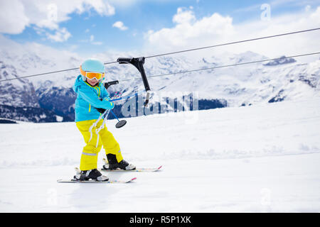 Enfant sur un bouton téléski montée dans les montagnes sur un jour de neige. Les enfants en hiver ecole de sport dans la région de alpine resort. Plaisir en famille dans la neige. L Banque D'Images