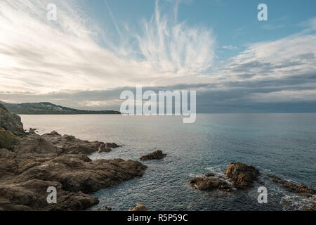 Les nuages filandreux soir alors que le soleil se couche sur la côte rocheuse en Balagne Corse Banque D'Images