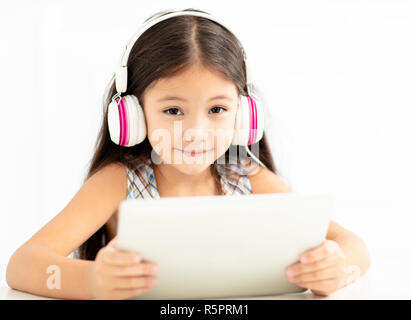 Smiling girl in et casque à l'aide de tablet Banque D'Images