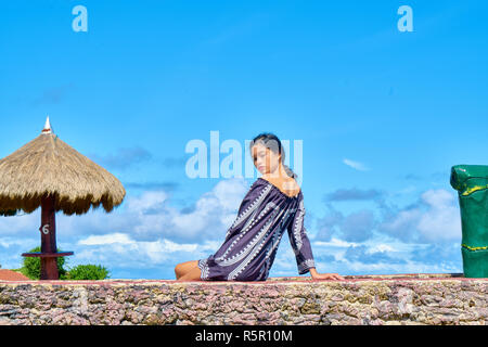 Beautiful woman posing - sitting on rock, à l'écart Banque D'Images