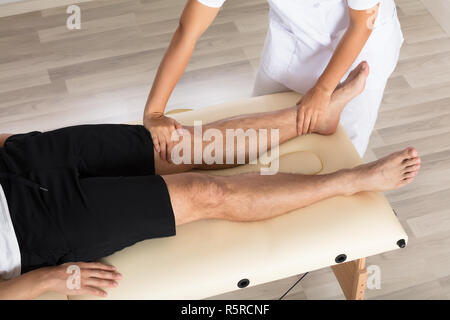 Physiothérapeute Massaging Man's Leg Banque D'Images